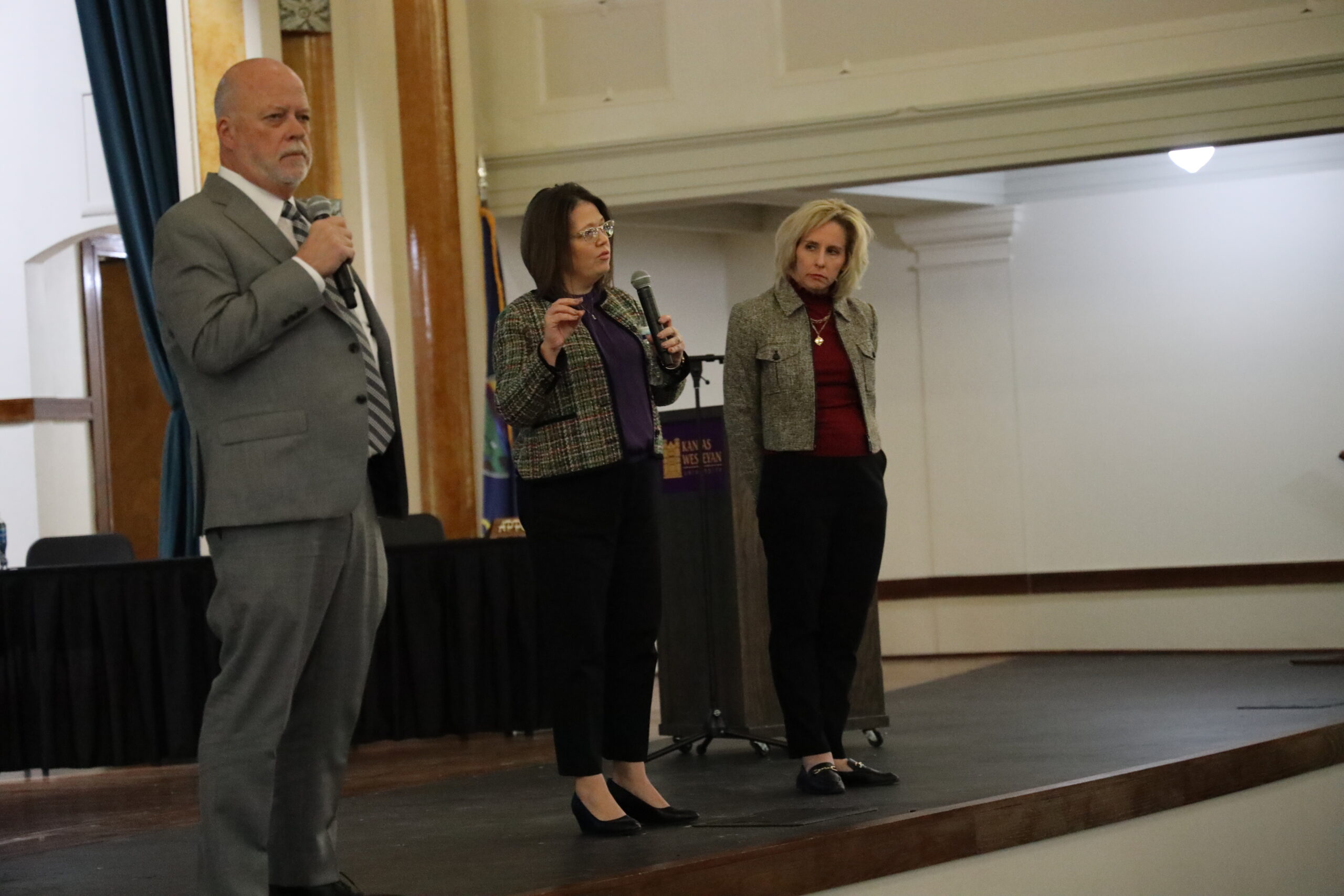 Three individuals on stage with mics