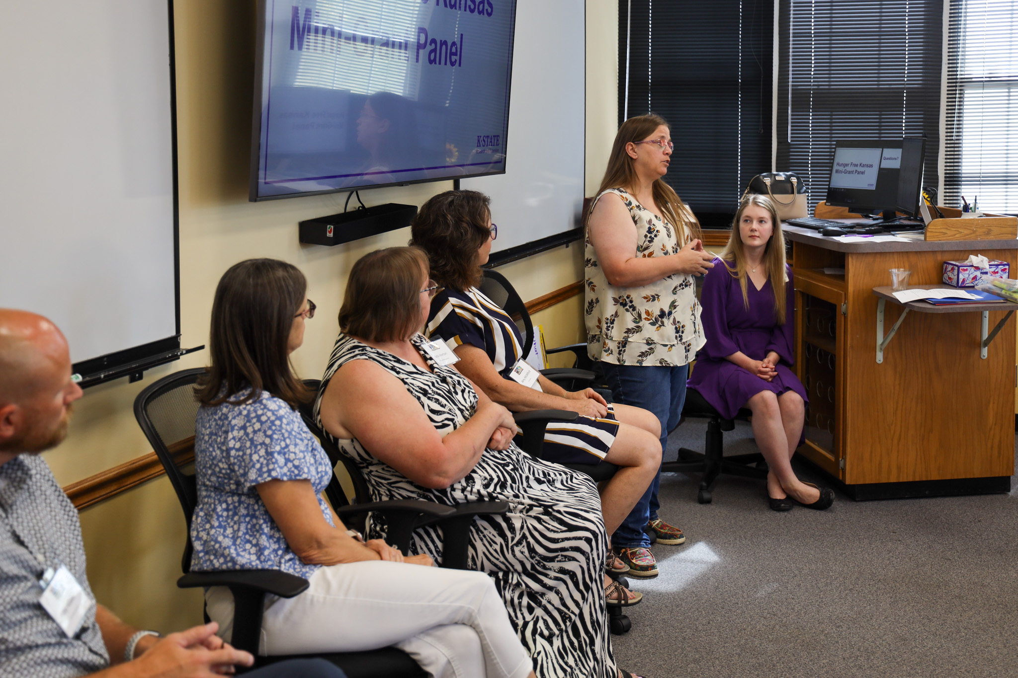 Panel discussion at front of room with one person standing and talking