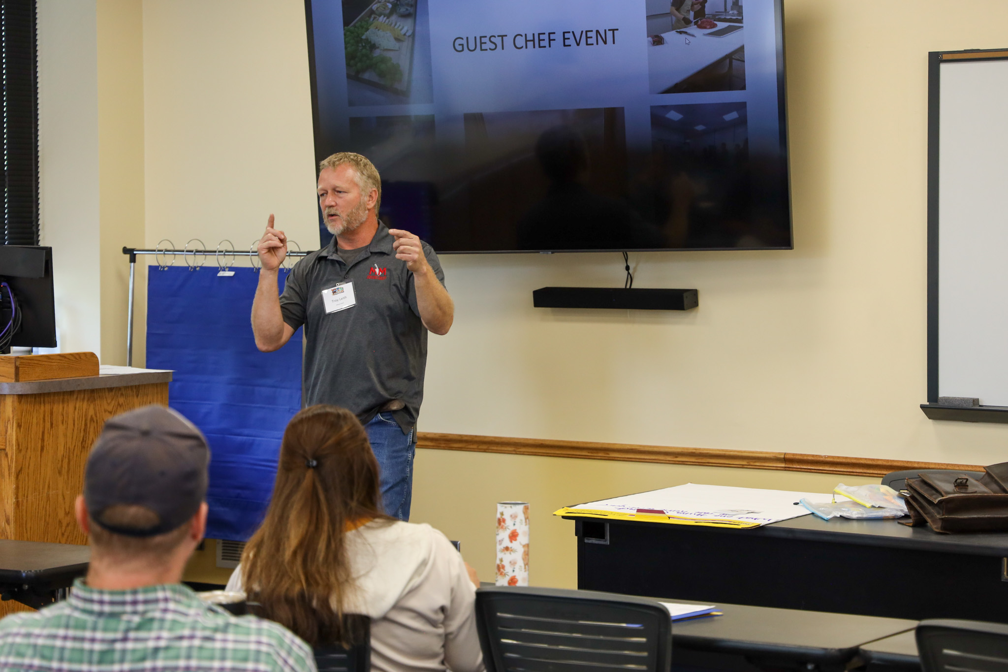 Man talking and gesturing in front of class