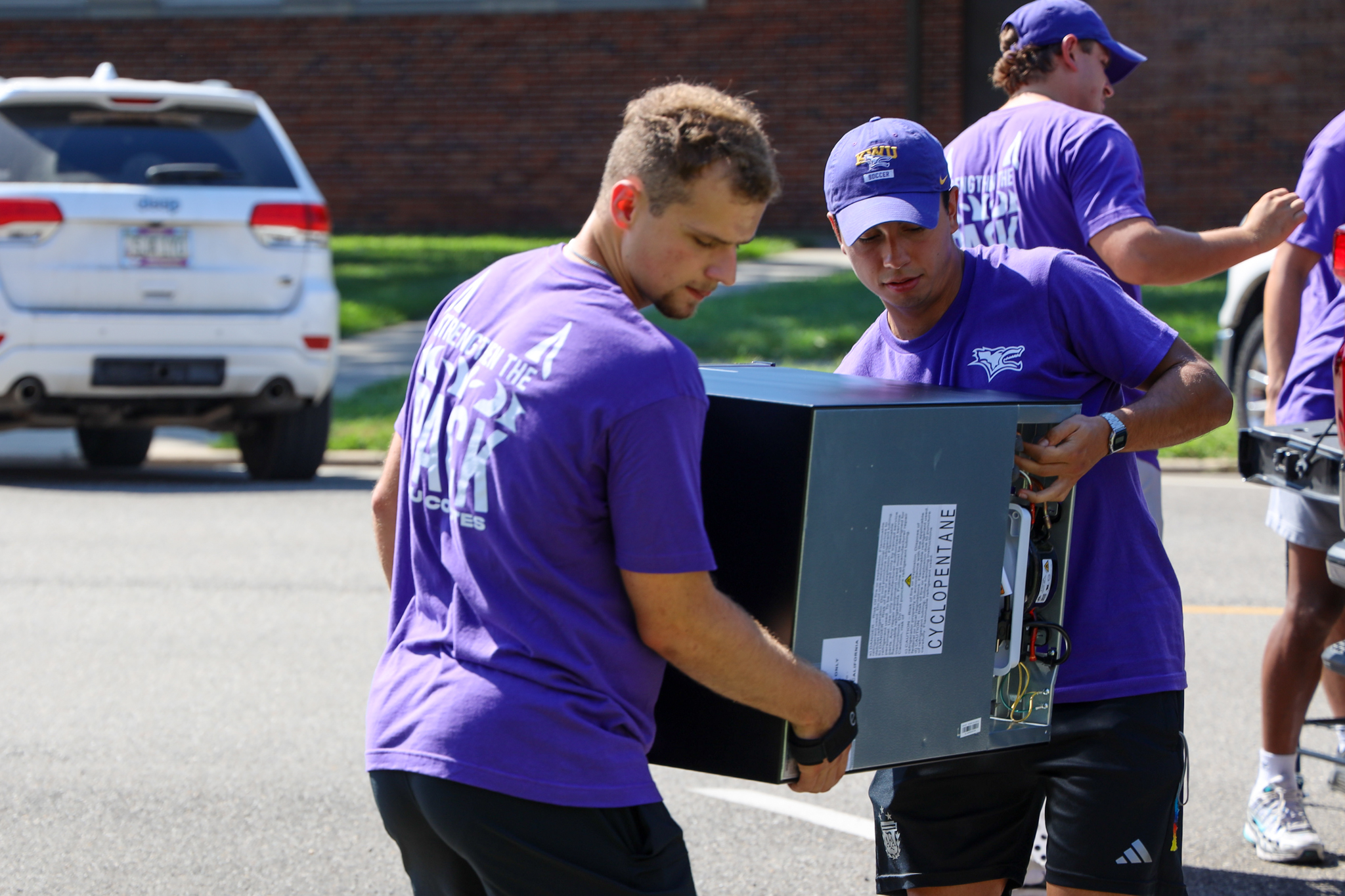 Two male students carrying item