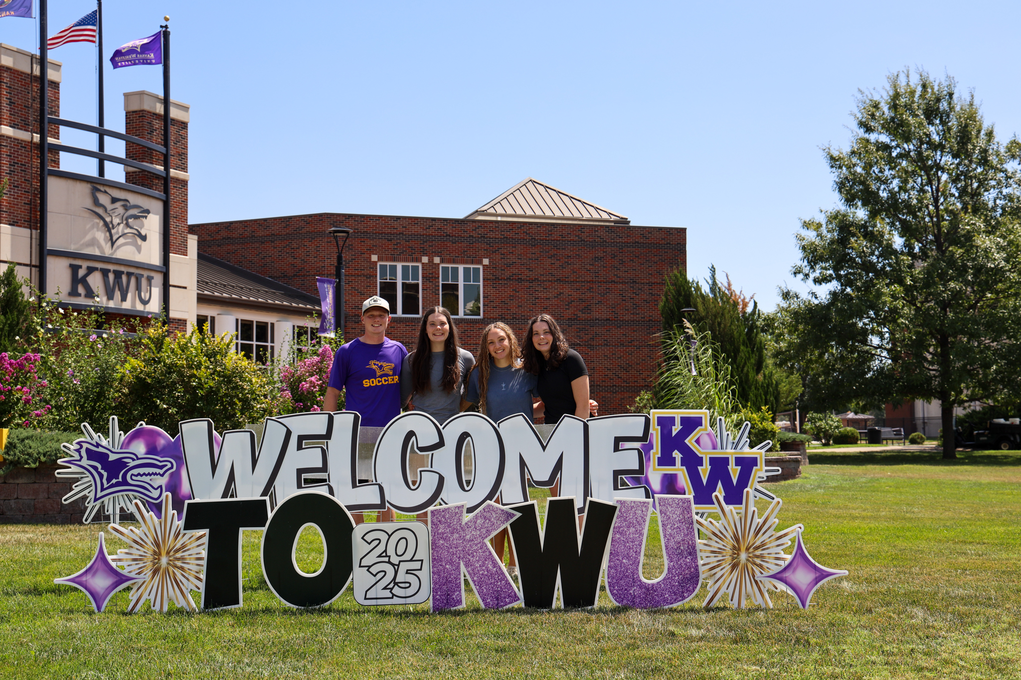 Group of students gathered behind welcome sign
