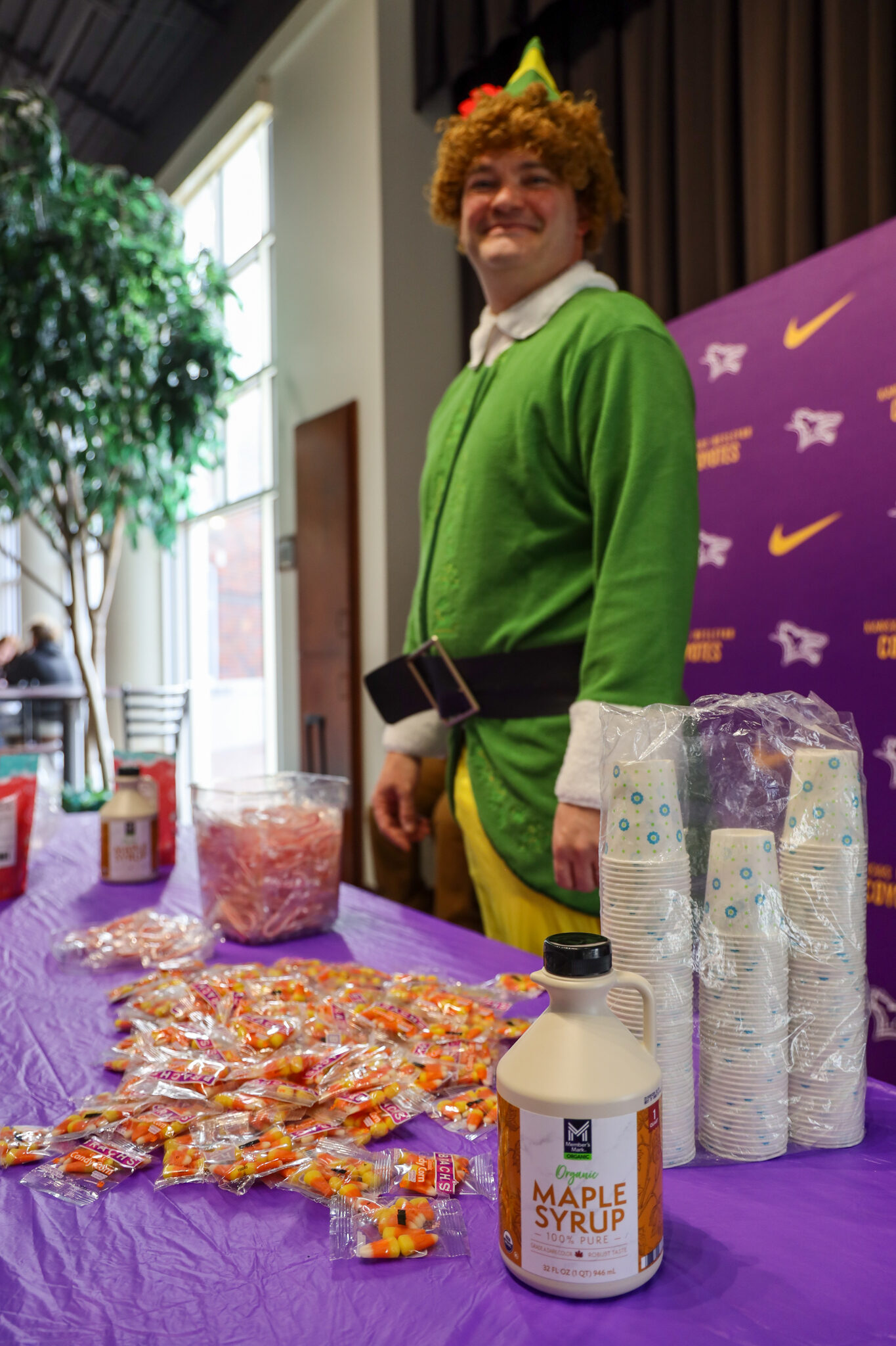 Man in elf costume talking to students