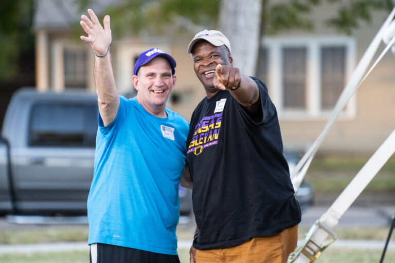 Two men pointing and waving at camera