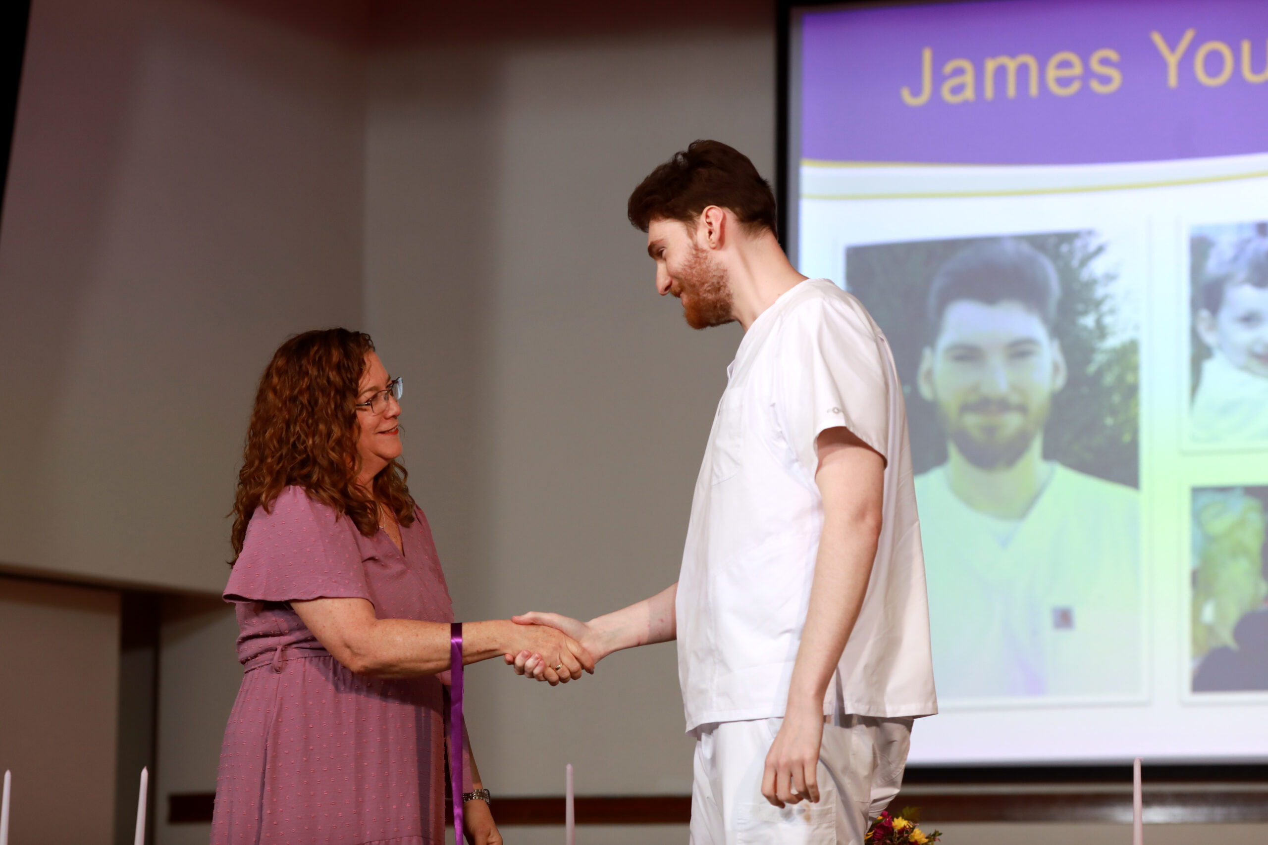 Woman shaking man's hand at nursing ceremony