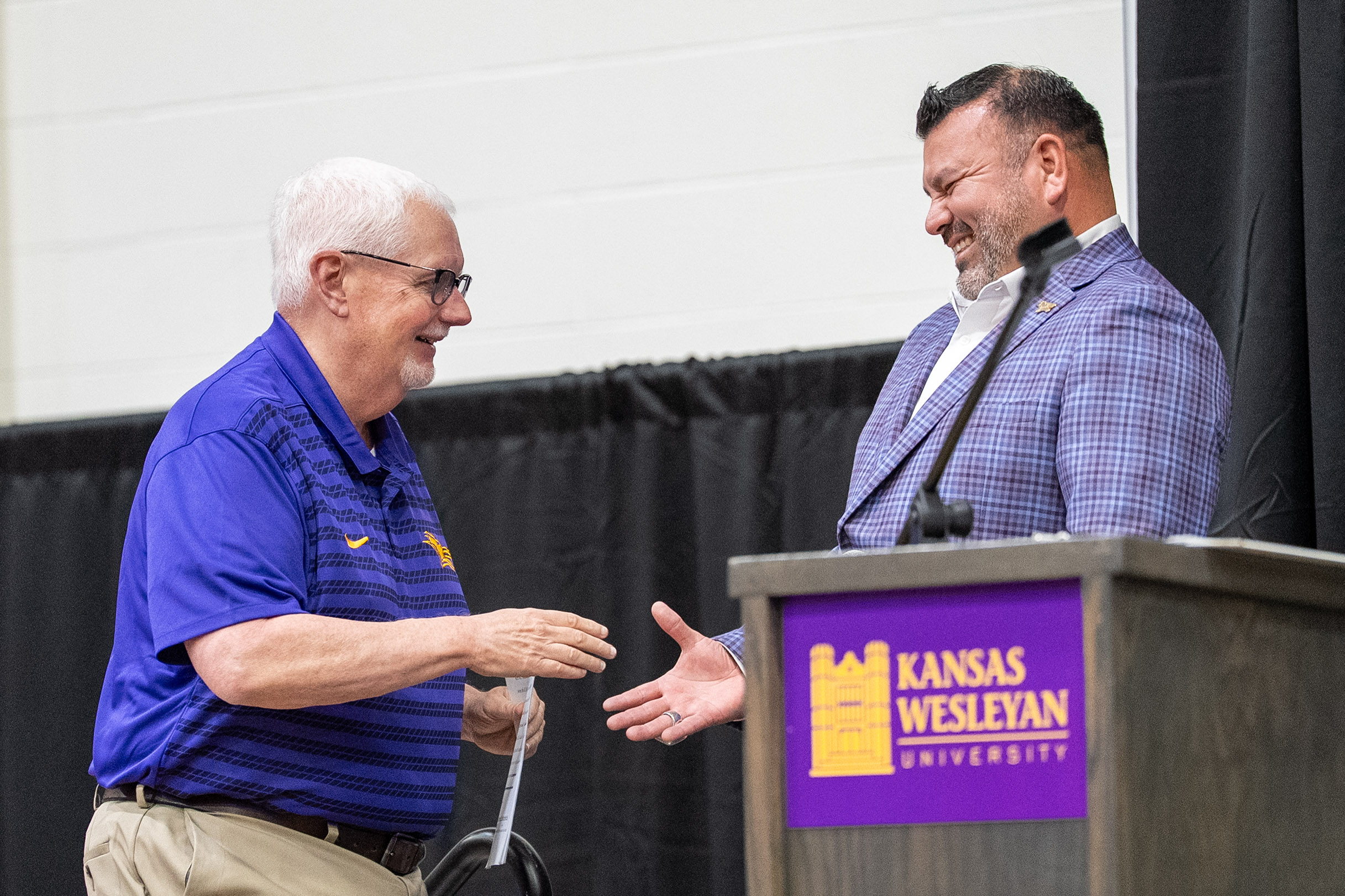 Man shaking hands with other man at podium