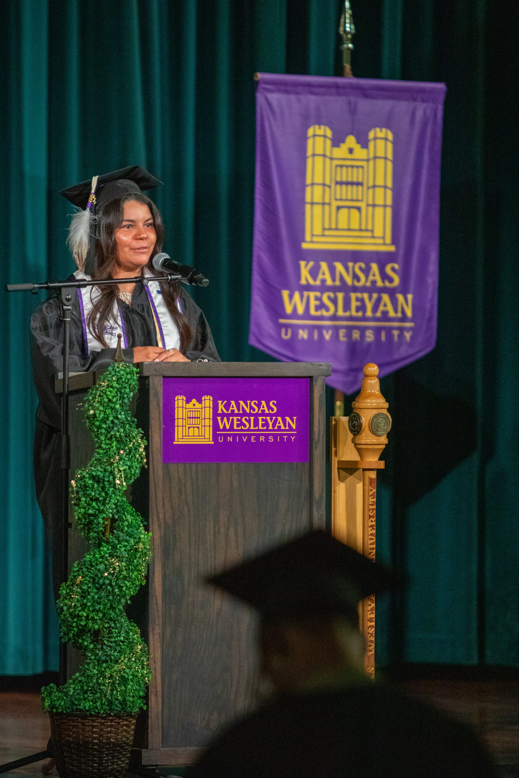Woman at platform in cap and gown singing