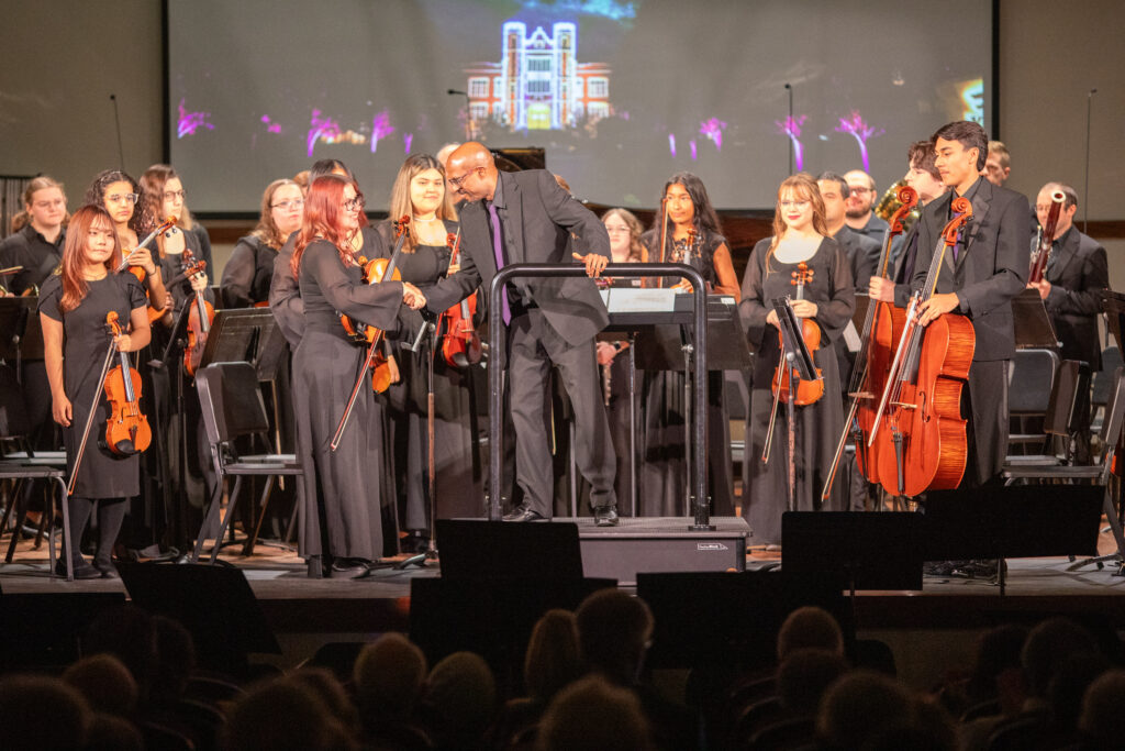 Man shaking hand of violinist, preparing to direct orchestra