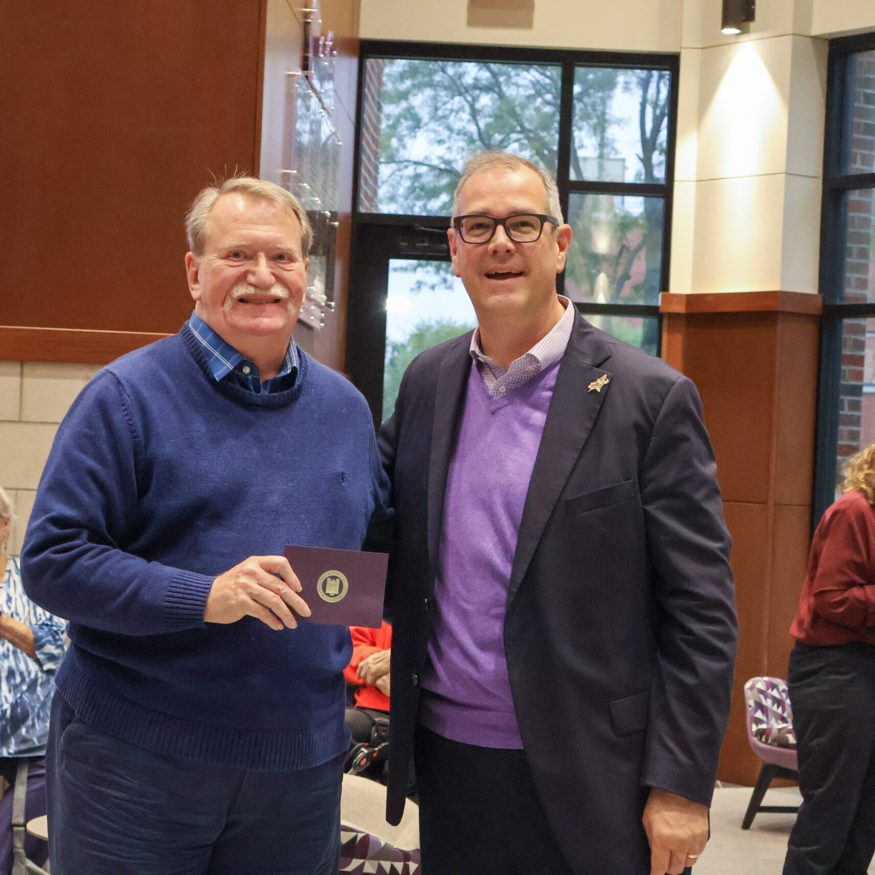 Two men by each other, one with award