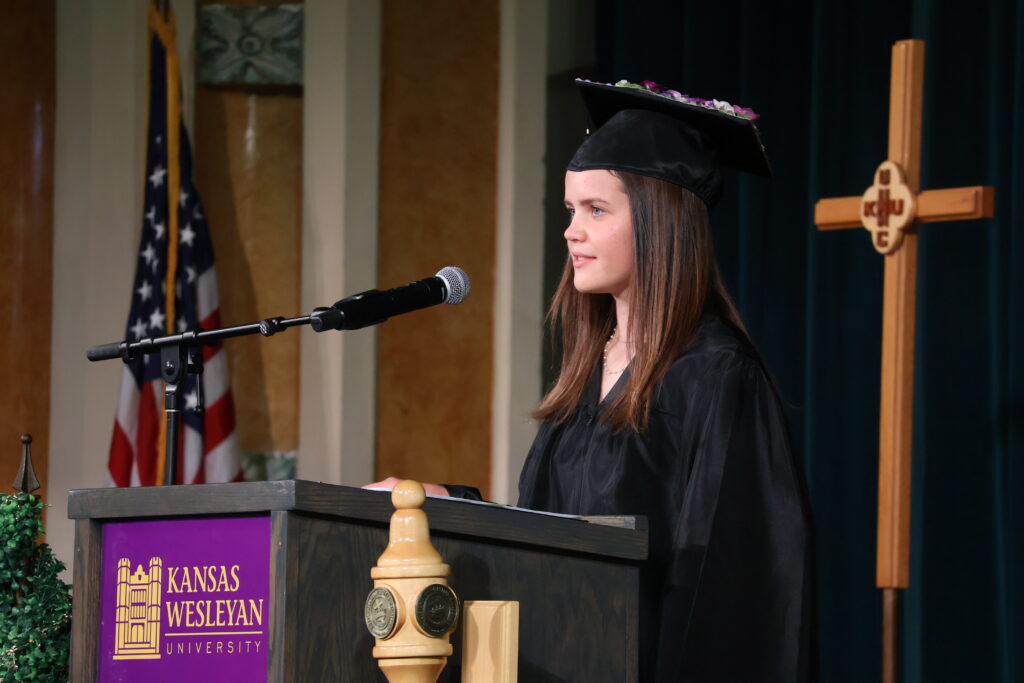Woman in cap and gown speaking at podium
