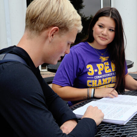 Two students work from a notebook.