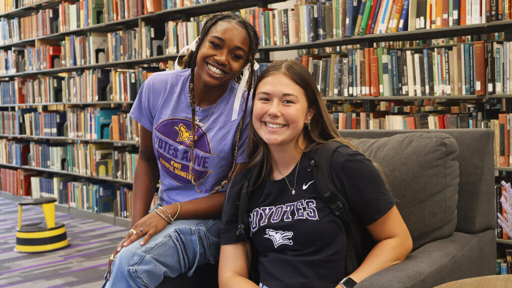 Two students pose for a photo together in the library.