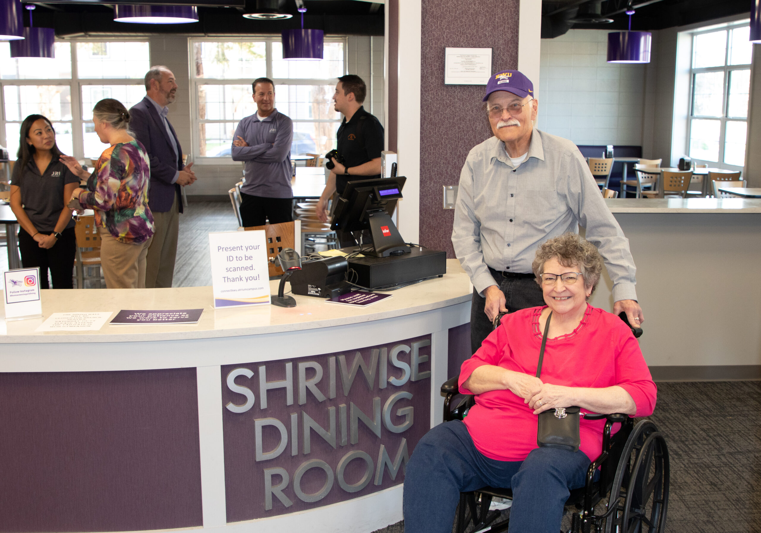 Man and woman in wheelchair next to dining room sign