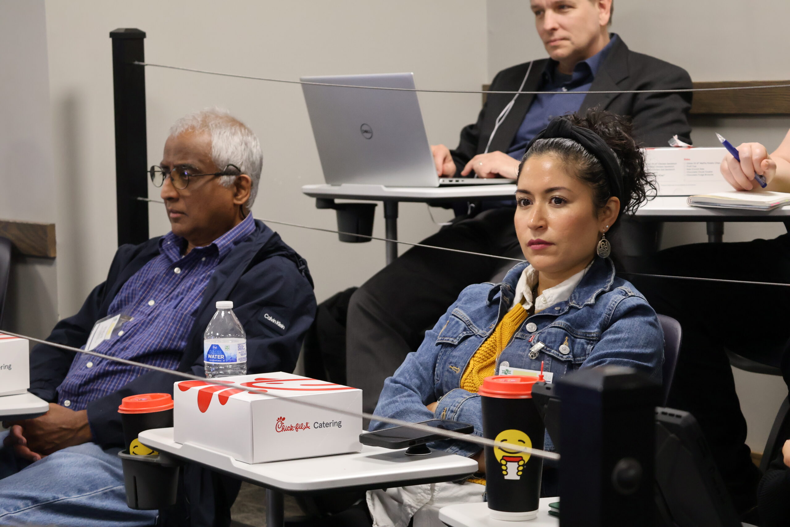 Man and woman sitting in chairs listening to speaker