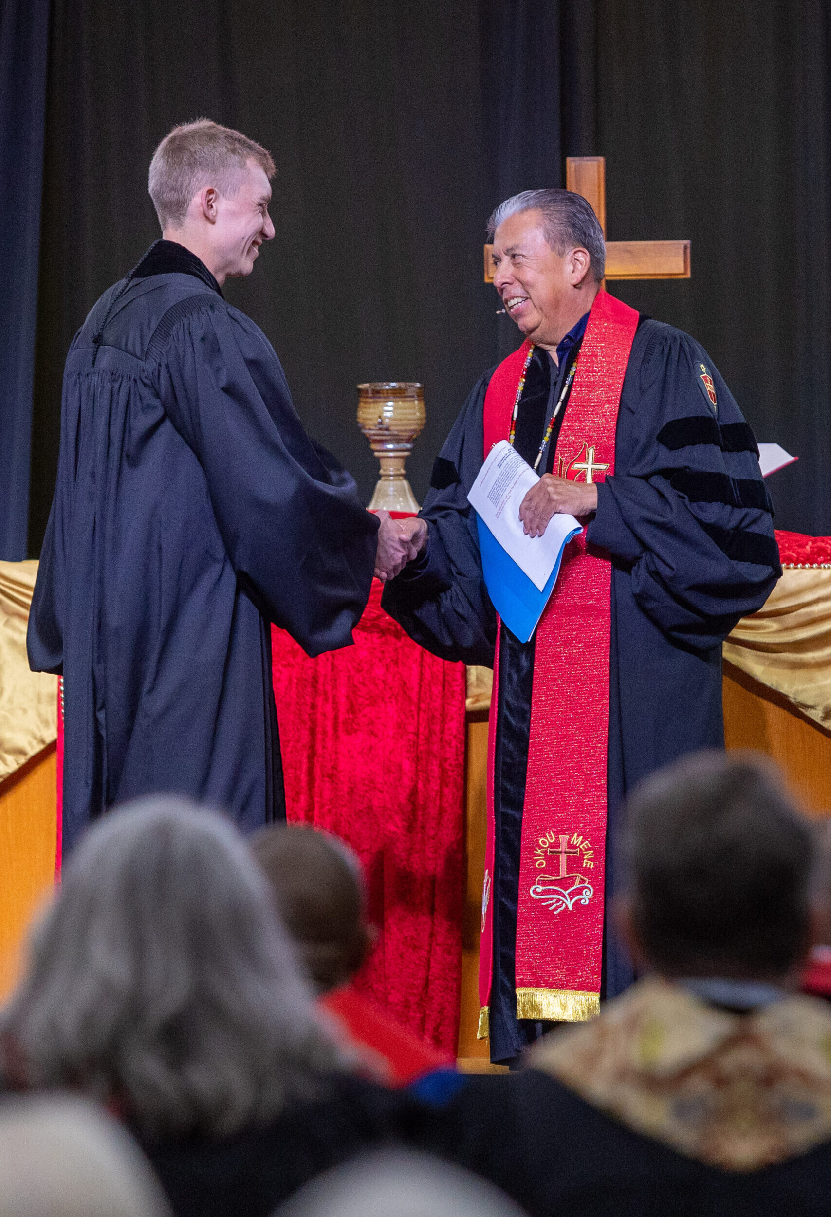 Various individuals in clergy robes on stage for ceremony